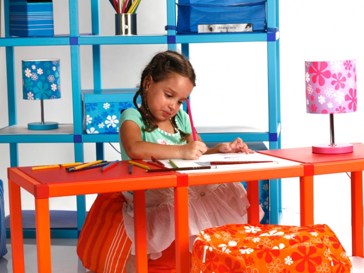 Holčička si kreslí na oranžovém stolku